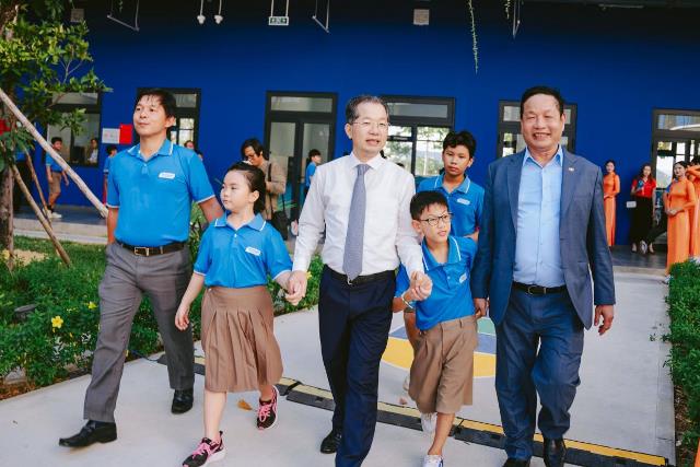 Bí thư Thành uỷ Đà Nẵng Nguyễn Văn Quảng (giữa), Chủ tịch Tập đoàn FPT Trương Gia Bình (phải) và Hiệu trưởng Trường Hy vọng dắt tay các em học sinh vào trường mới khánh thành