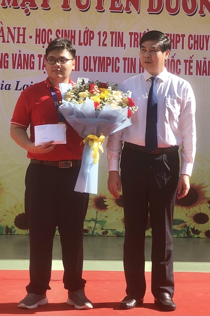 Ông Lâm Hải Giang (bên phải) tặng hoa và trao tiền thưởng của UBND tỉnh Gia Lai cho em Lê Kiên Thành. Ảnh: VH