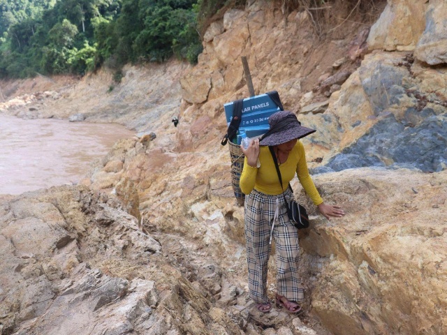 Người phụ nữ thận trọng quan sát, đặt từng bước chân lên mặt đá sắc nhọn để vận chuyển thực phẩm.