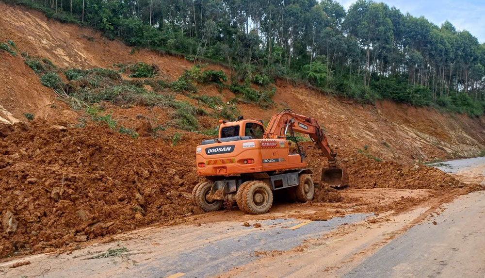 Lực lượng chức năng bố trí máy móc hót dọn đất sạt lở trên đường tỉnh 294B đoạn qua xã Xuân Lương.