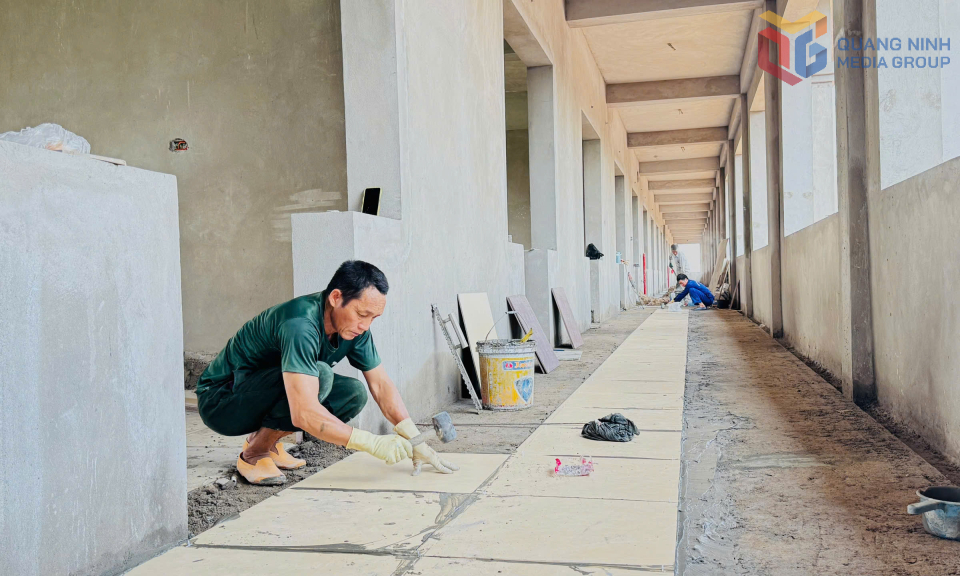 Công nhân đang thực hiện ốp lát nền các khối nhà Trường THCS Hồng Thái Đông.