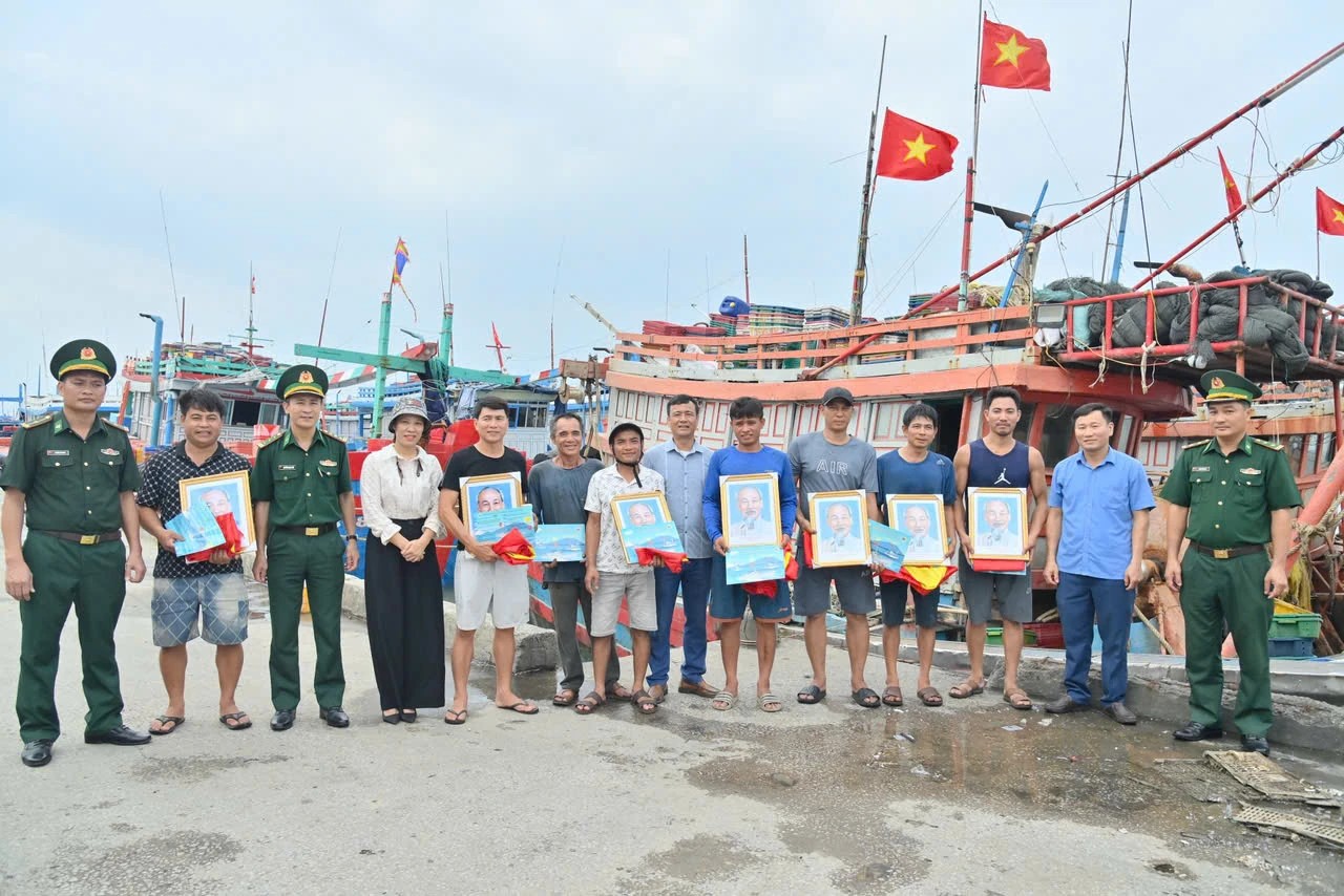 Cán bộ, chiến sĩ Ban Chỉ huy Biên phòng CKC Nghi Sơn và lãnh đạo phường Hải Bình xuống tàu trao cờ tổ quốc, ảnh Bác Hồ và tuyên truyền chống khai thác IUU cho ngư dân.