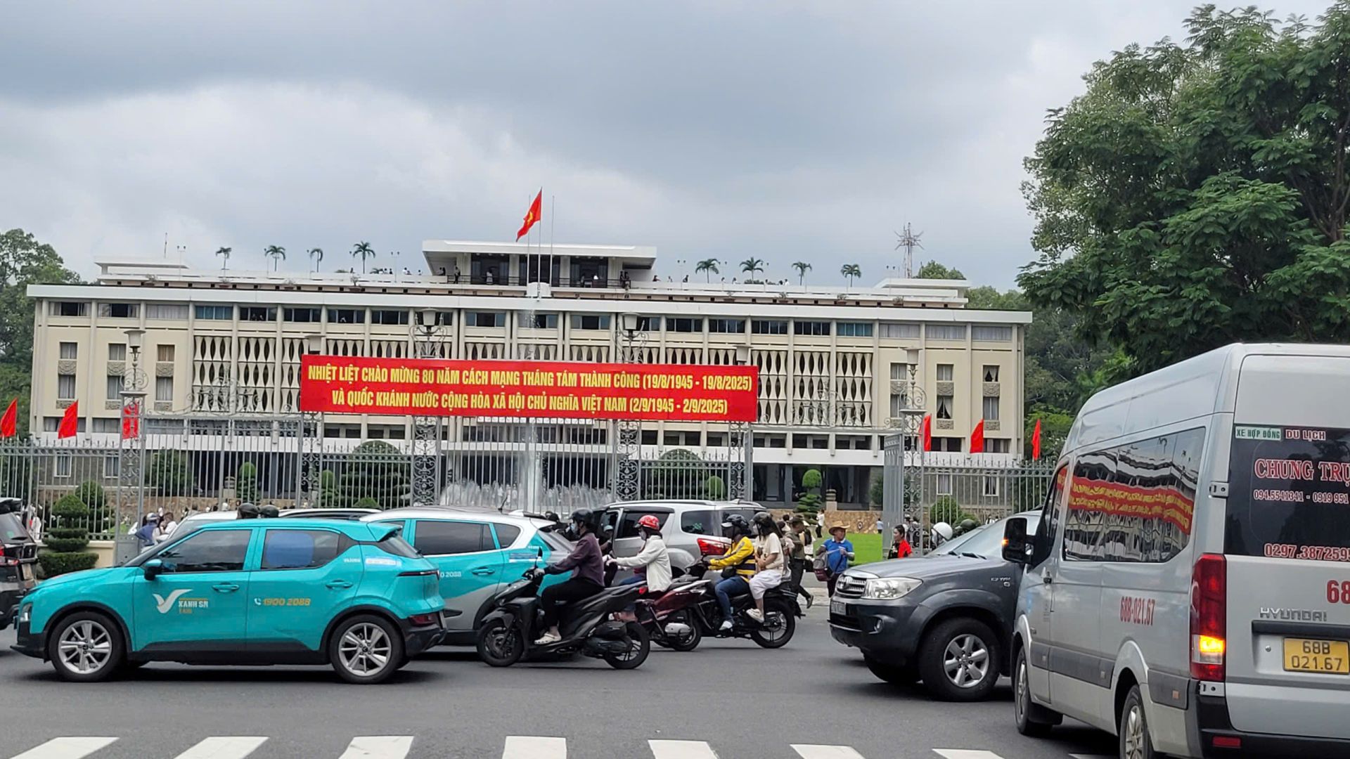 Tại Dinh Độc Lập, dù thời tiết không mấy thuận lợi, đông đảo người dân và du khách vẫn diện áo đỏ sao vàng, áo dài để chụp ảnh, lưu giữ khoảnh khắc ý nghĩa