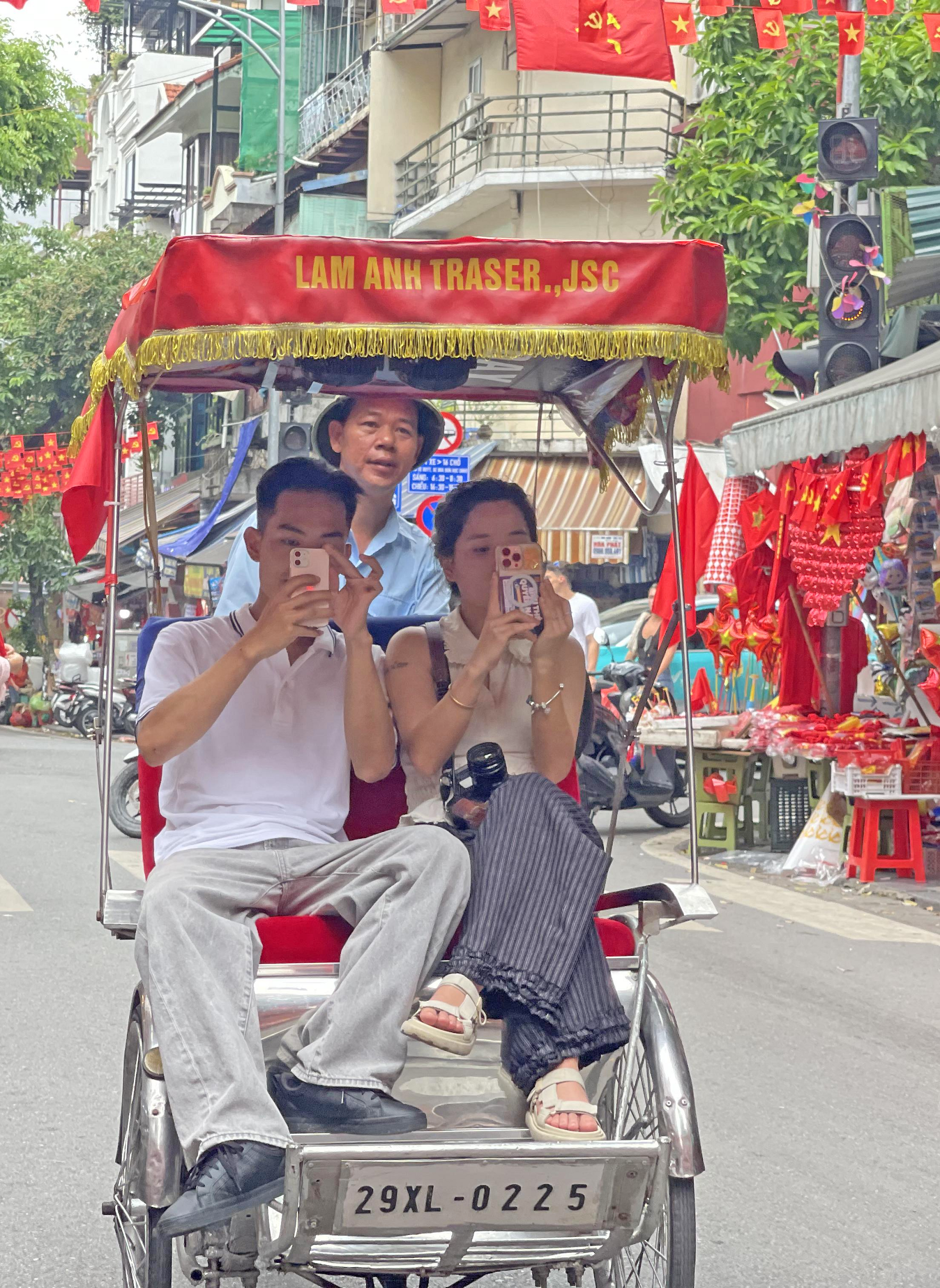 Khách du lịch ngồi trên xe xích lô, tận hưởng không khí rộn rã và sắc cờ đỏ sao vàng trên phố Hàng Chiếu, Hà Nội dịp Quốc khánh 2/9.
