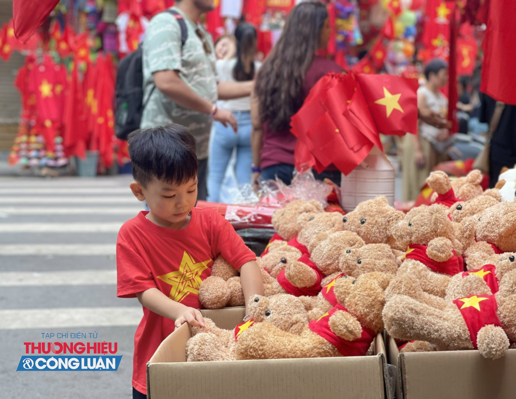 Em bé thích thú ngắm gấu bông trên phố Hàng Lược, trong không khí rộn rã và sắc cờ đỏ sao vàng chào mừng Quốc khánh 2/9.