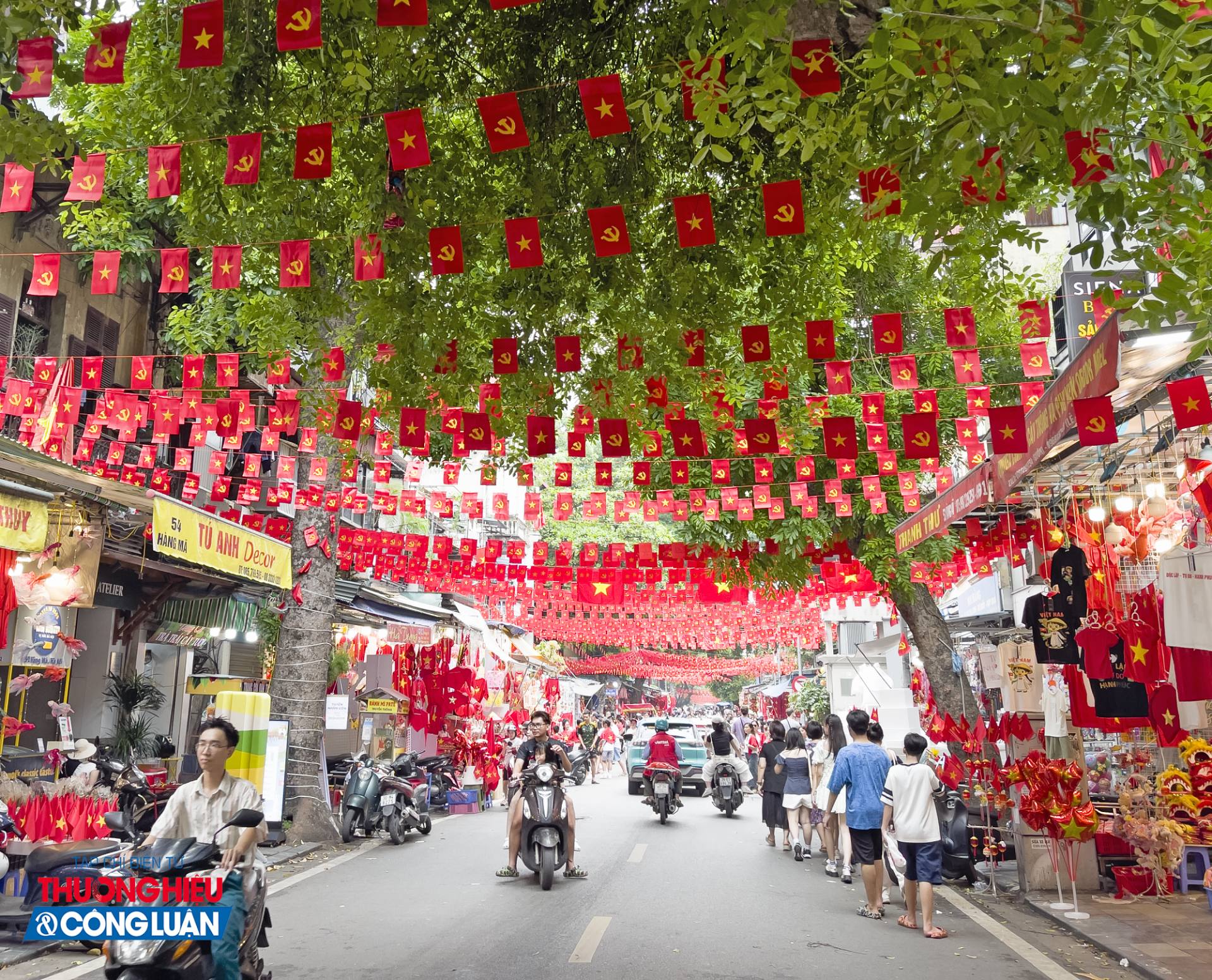 Sắc đỏ rực rỡ của những lá cờ sao vàng trải dài trên phố Hàng Mã, hòa cùng không khí nhộn nhịp và tiếng rộn rã của người dân, tạo nên một khung cảnh tưng bừng như ngày hội.