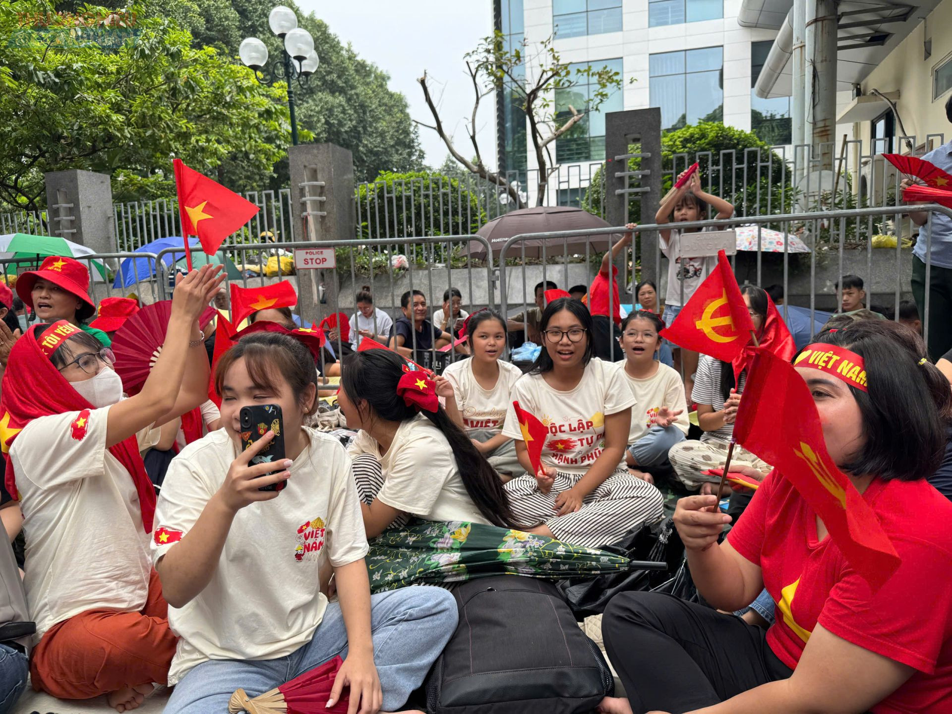 Người dân mang theo cờ đỏ sao vàng, băng rôn, áo cờ Tổ quốc rực rỡ, háo hức chờ diễu binh mừng Quốc khánh 2/9 tại Hà Nội.