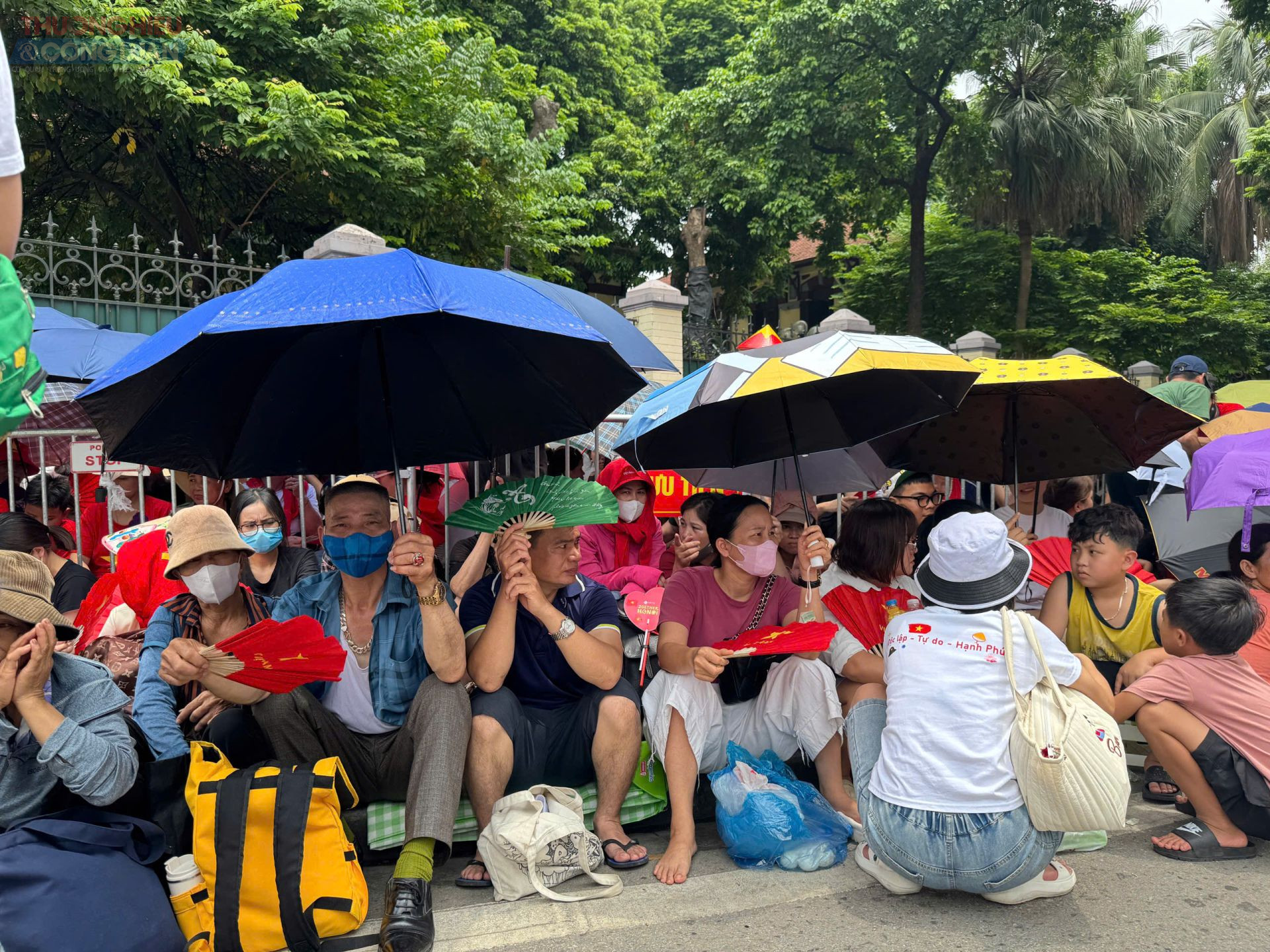 Người dân che ô, quạt tay ngồi kín vỉa hè Hà Nội chờ xem diễu binh 2/9.
