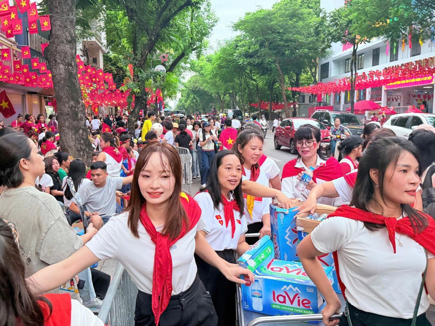 Các cô giáo kéo xe nước phát cho người dân đứng hai bên đường Nguyễn Thái Học chờ xem tổng duyệt A80.