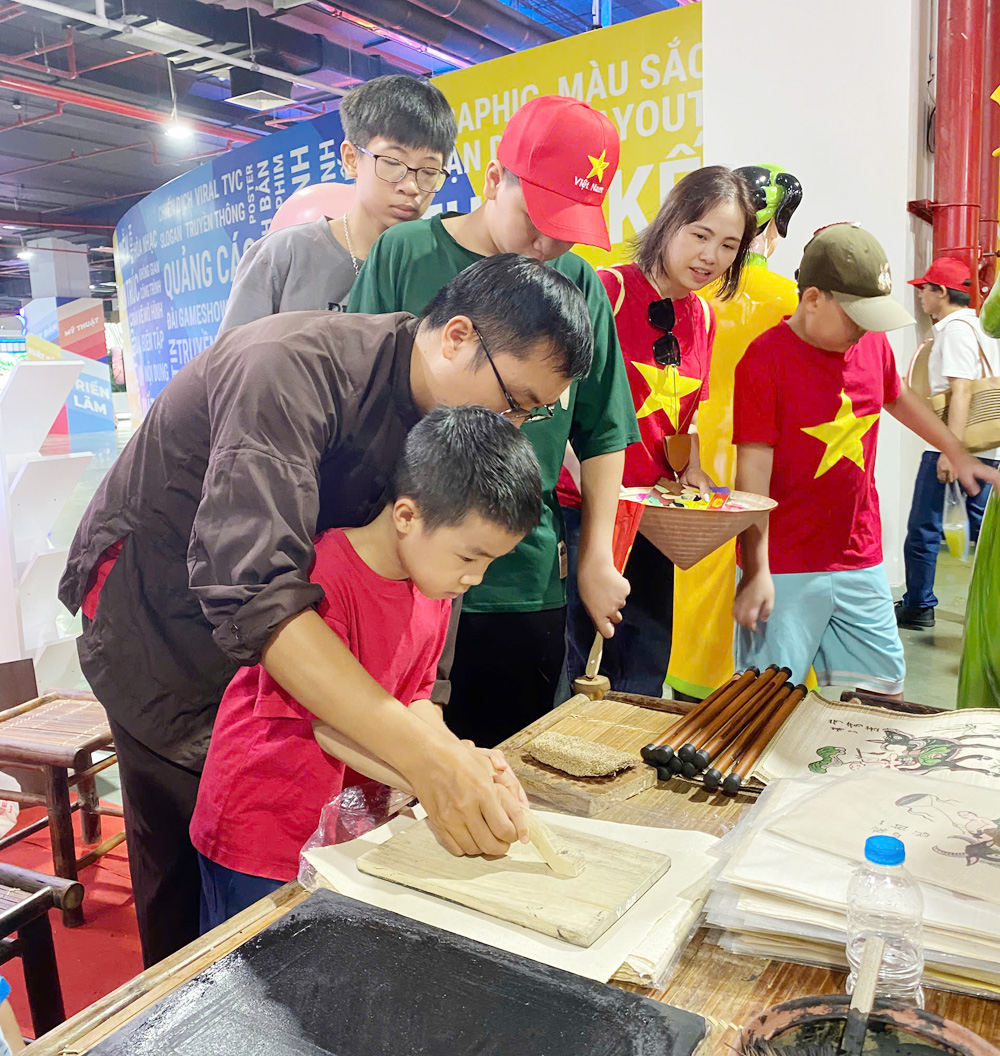 Các em nhỏ trải nghiệm kỹ thuật in tranh Đông Hồ tại gian trưng bày của tỉnh Bắc Ninh.