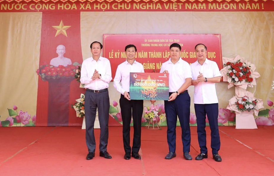 Ông Đinh Tiến Hải, Giám đốc Quỹ bảo trợ trẻ em Việt Nam (ngoài cùng bên phải) và ông Hồng Quang, Thành viên HĐQT, Chủ tịch Công đoàn Vietcombank (thứ 2 từ phải sang) trao biển tượng trưng 80 suất học bổng cho 6 trường trên địa bàn xã Tân Trào, tỉnh Tuyên Quang