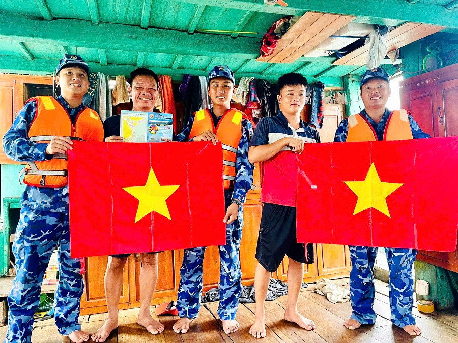 Tổ công tác tàu CSB 1014 phát tờ rơi tuyên truyền và tặng cờ Tổ quốc cho ngư dân trên tàu cá QB-93949-TS