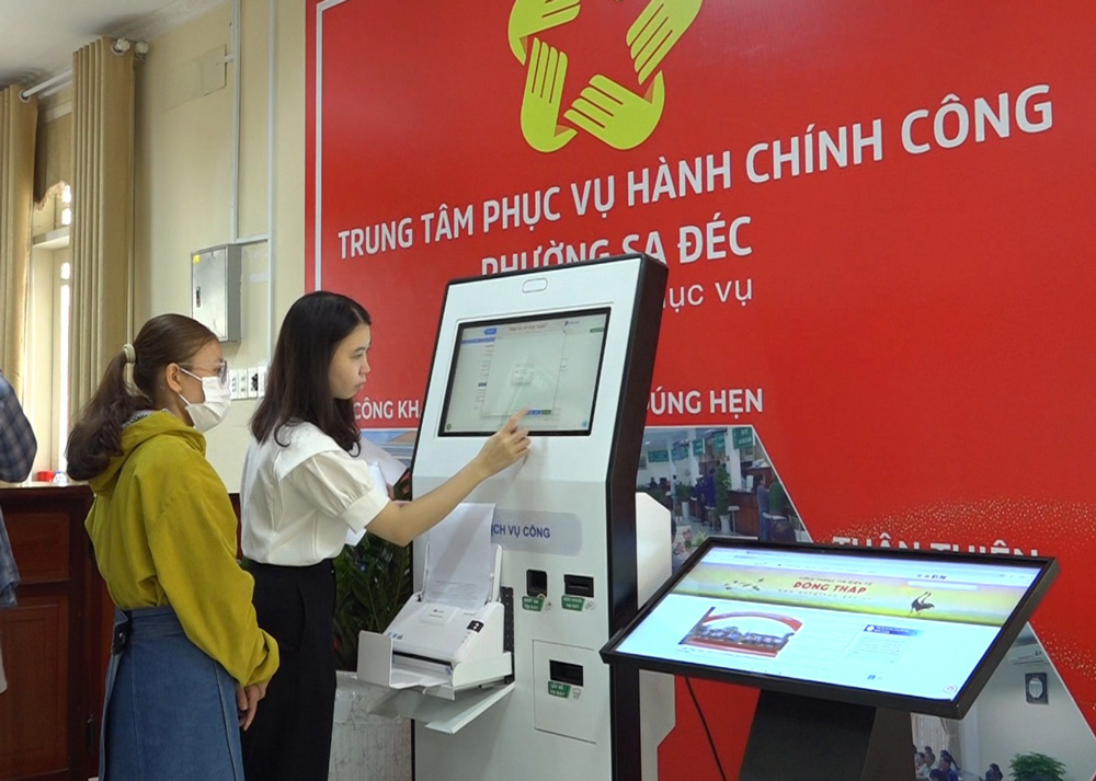 Công chức hướng dẫn người dân nộp hồ sơ trực tuyến tại ki-ốt thông minh. Ảnh: Ngọc Duy