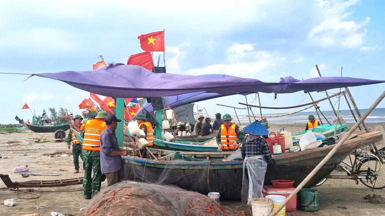 Cán bộ, chiến sĩ Đồn Biên phòng giúp ngư dân chằng chống tàu thuyền.