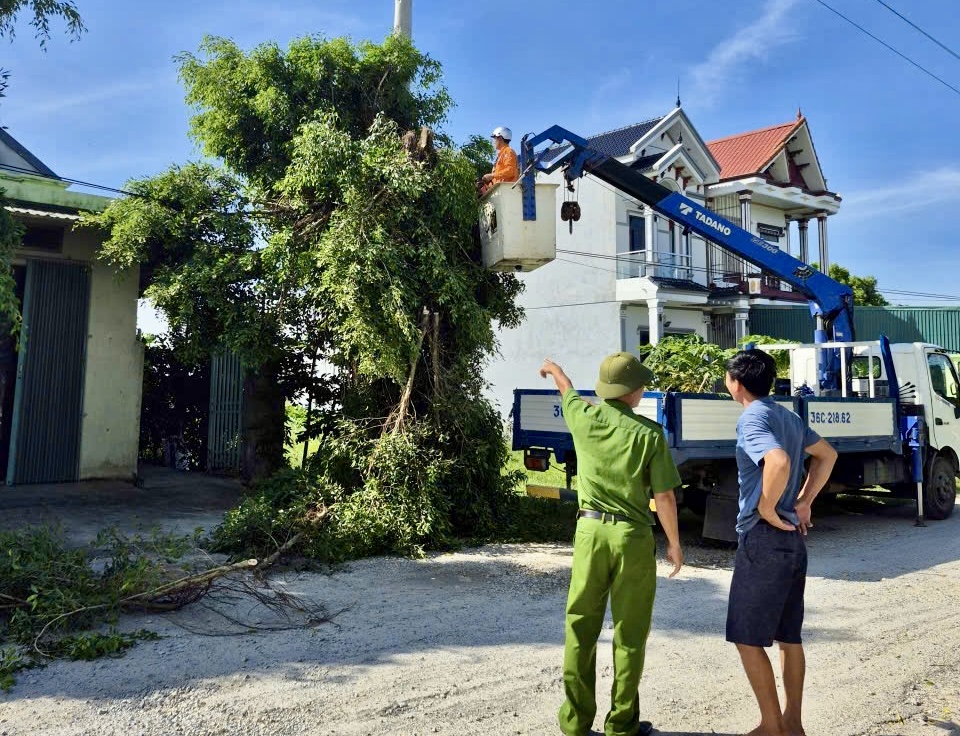 Công an xã Tân Tiến Tham phối hợp với công ty điện lực cắt tỉa các cành cây to tiềm ẩn gãy đổ để bảo đảm an toàn