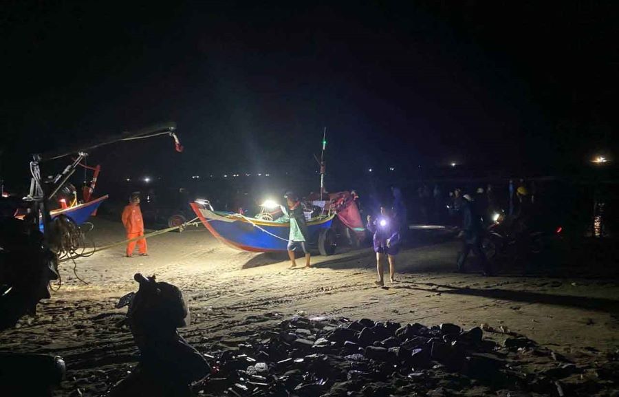 Lực lượng chức năng cùng người dân kéo dắt thuyền cá gặp nạn vào bờ.