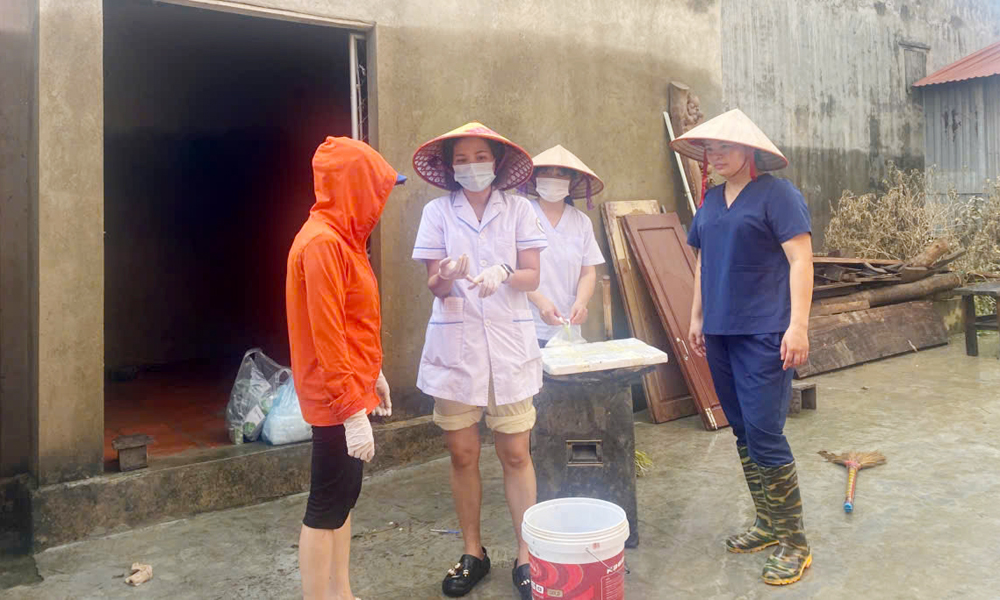 Cán bộ Trạm y tế xã Tam Giang hướng dẫn người dân thôn Đồng Nhân vệ sinh khử trùng sau ngập.