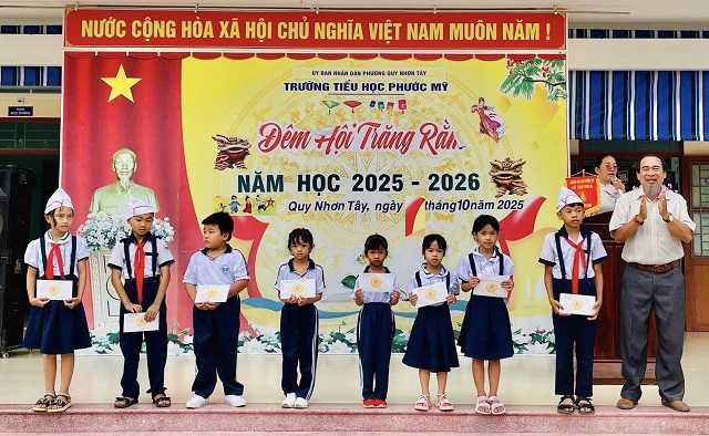 Ông Phạm Thao (bìa phải) trao quà cho học sinh Trường Tiểu học Phước Mỹ Ảnh: VH