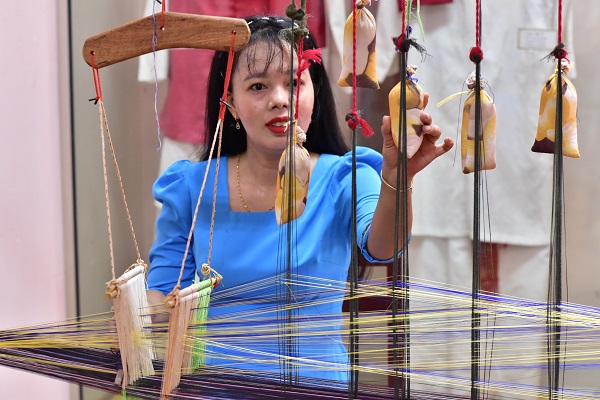 Người dân và du khách trải nghiệm dệt thổ cảm Chăm tại nhà trưng bày trong khu di tích Tháp Pô Klong Garai.