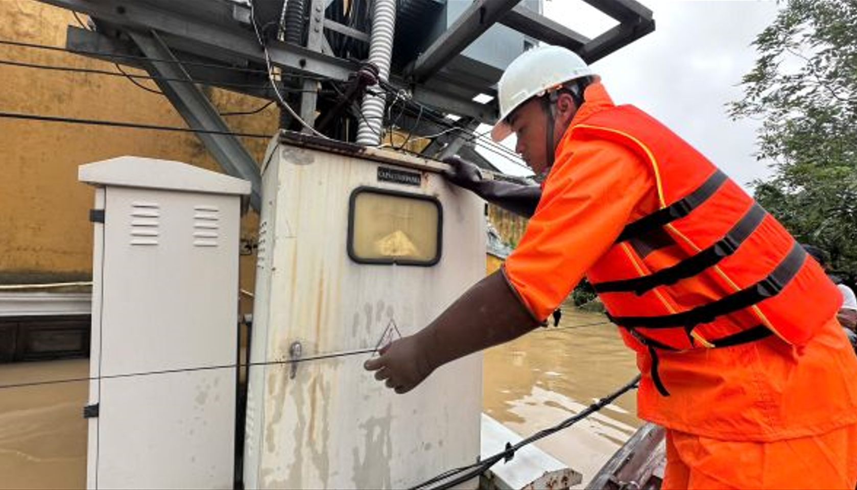 Công nhân Công ty Điện lực Đà Nẵng kiểm tra hệ thống điện tại vùng ngập Hội An. Ảnh: HL