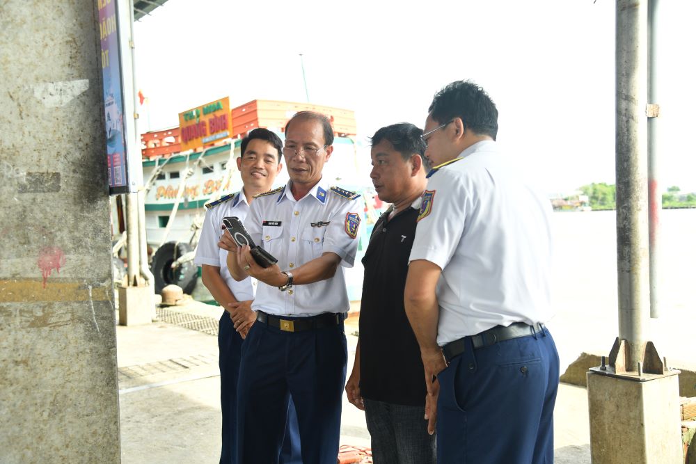 Cán bộ BTL Vùng Cảnh sát biển 4 triển khai pano tuyên truyền tại cảng cá Sông Đốc và hướng dẫn cho bà con ngư dân quét mã QR tra cứu các quy định pháp luật về chống khai thác IUU.