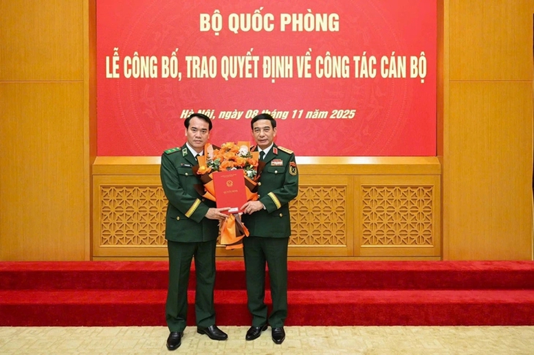 Thừa ủy quyền của Chủ tịch nước, Thủ tướng Chính phủ, Đại tướng Phan Văn Giang, Bộ trưởng Bộ Quốc phòng, trao quyết định và tặng hoa chúc mừng Trung tướng Vũ Trung Kiên (bên trái)
