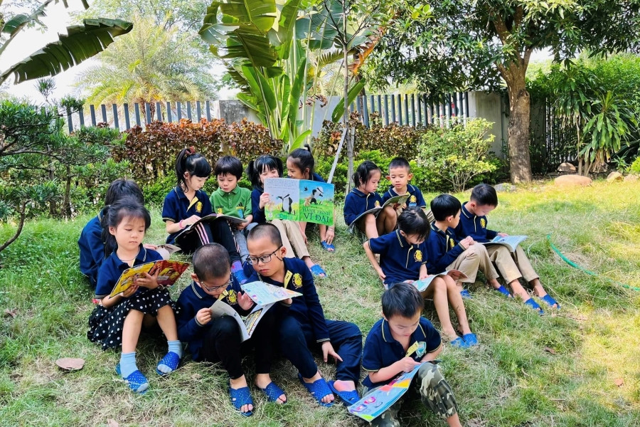 Những phút thư giãn của học sinh khi cùng nhau đọc sách ngoài sân trường, lan tỏa niềm yêu sách trong không gian học tập xanh.