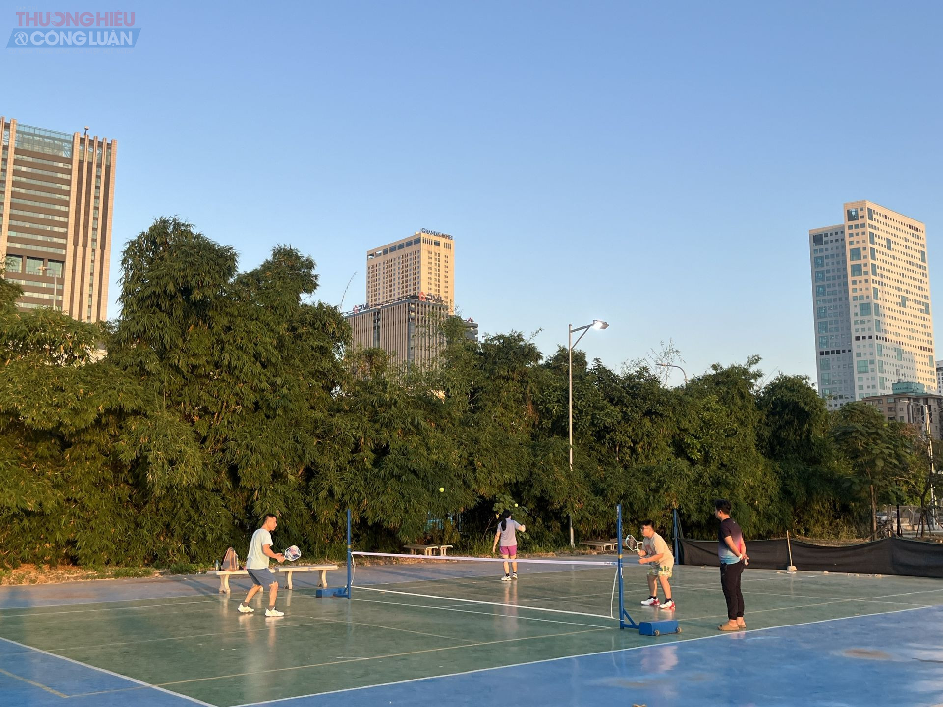 Một gia đình tập pickleball tại sân thể thao, tiếng cười nói rộn rã, hoạt động vừa vui vẻ vừa tăng cường sức khỏe.