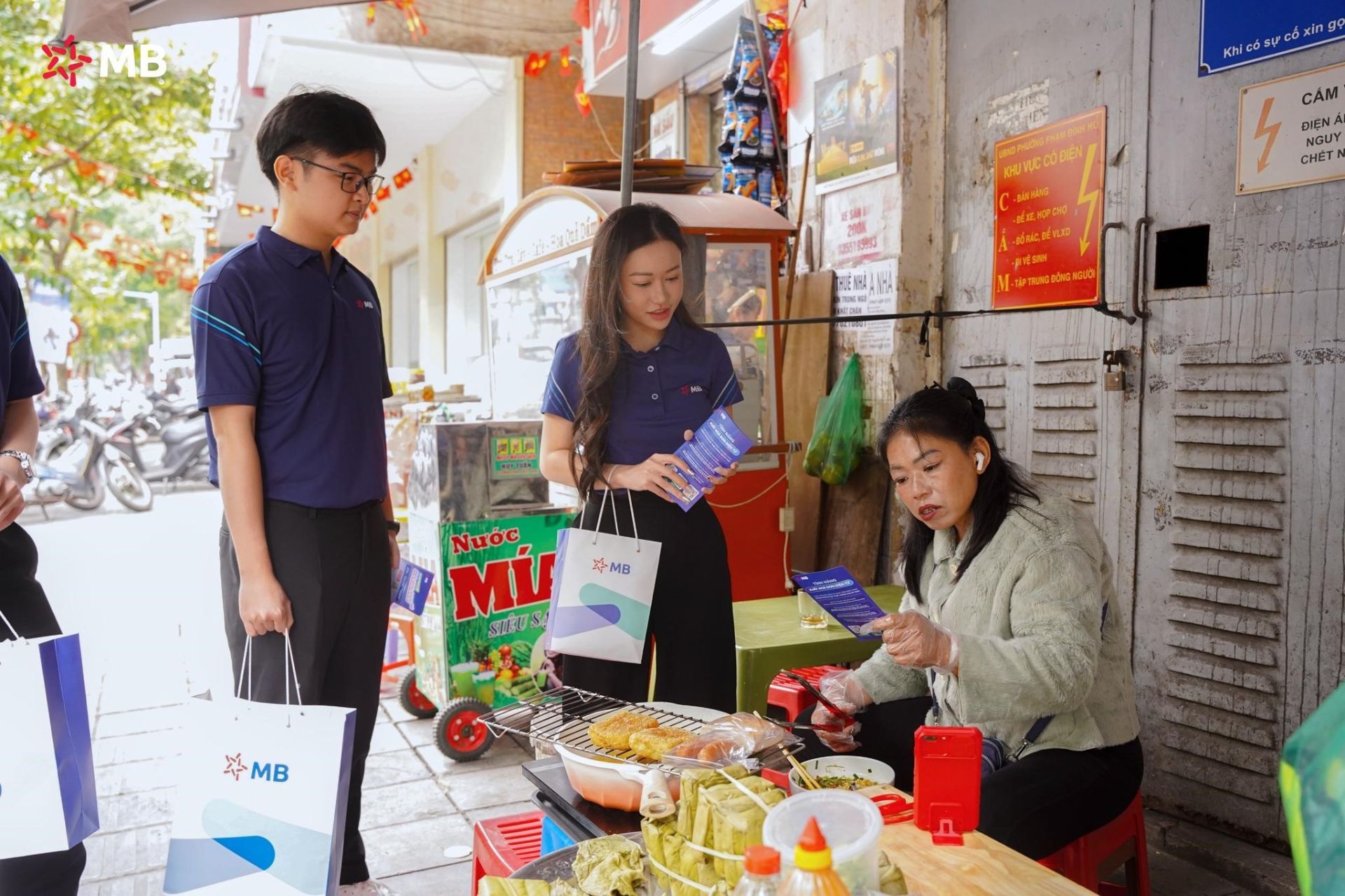 Nhân viên MB hướng dẫn tiểu thương chợ Hôm chuyển đổi số Nhân viên MB hướng dẫn tiểu thương chợ Hôm chuyển đổi số