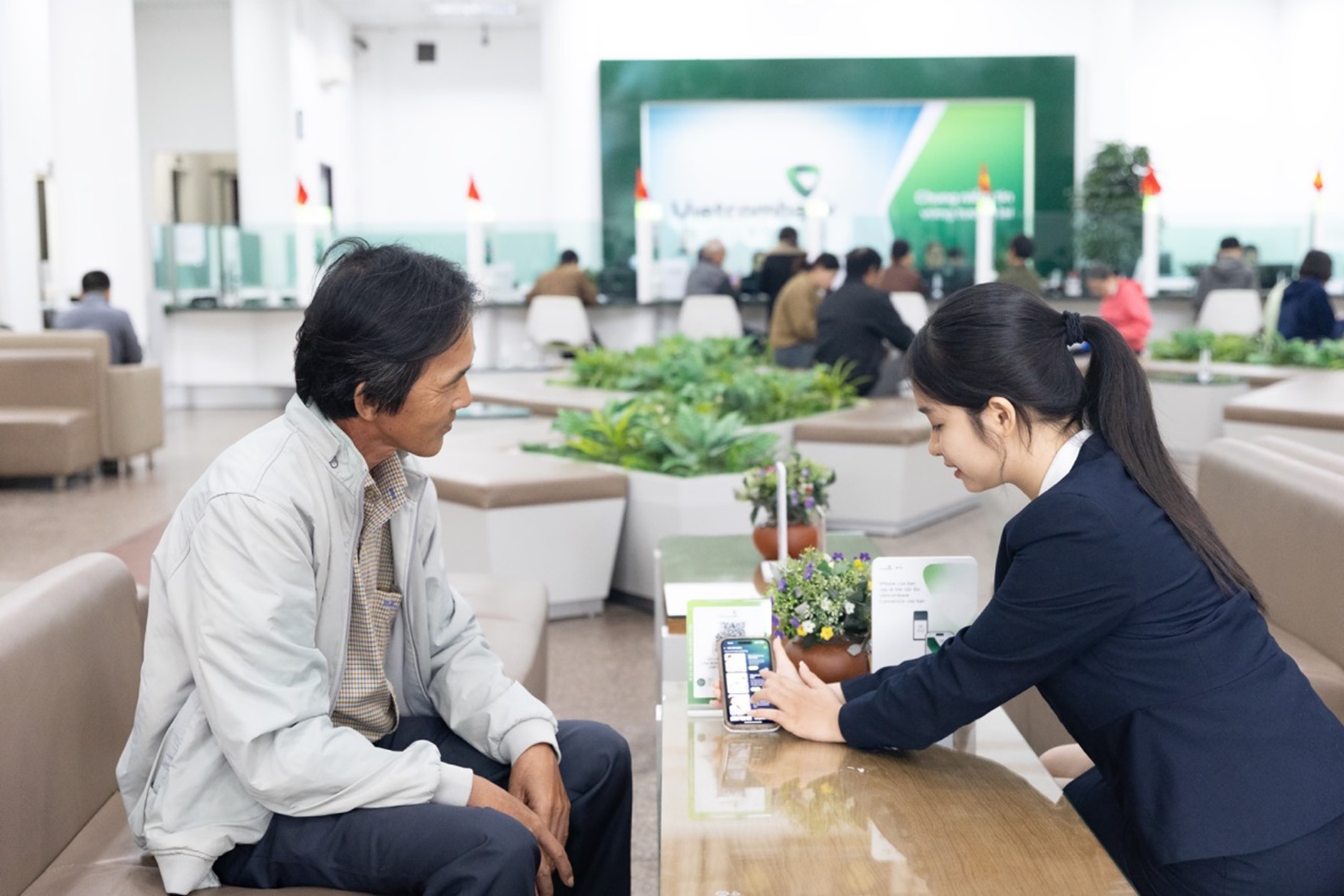 Cán bộ Vietcombank hướng dẫn anh Tấn Điệp sử dụng các tiện ích số và phổ biến về chương trình giai đoạn 2 “Để hạnh phúc nhân ba” tại quầy