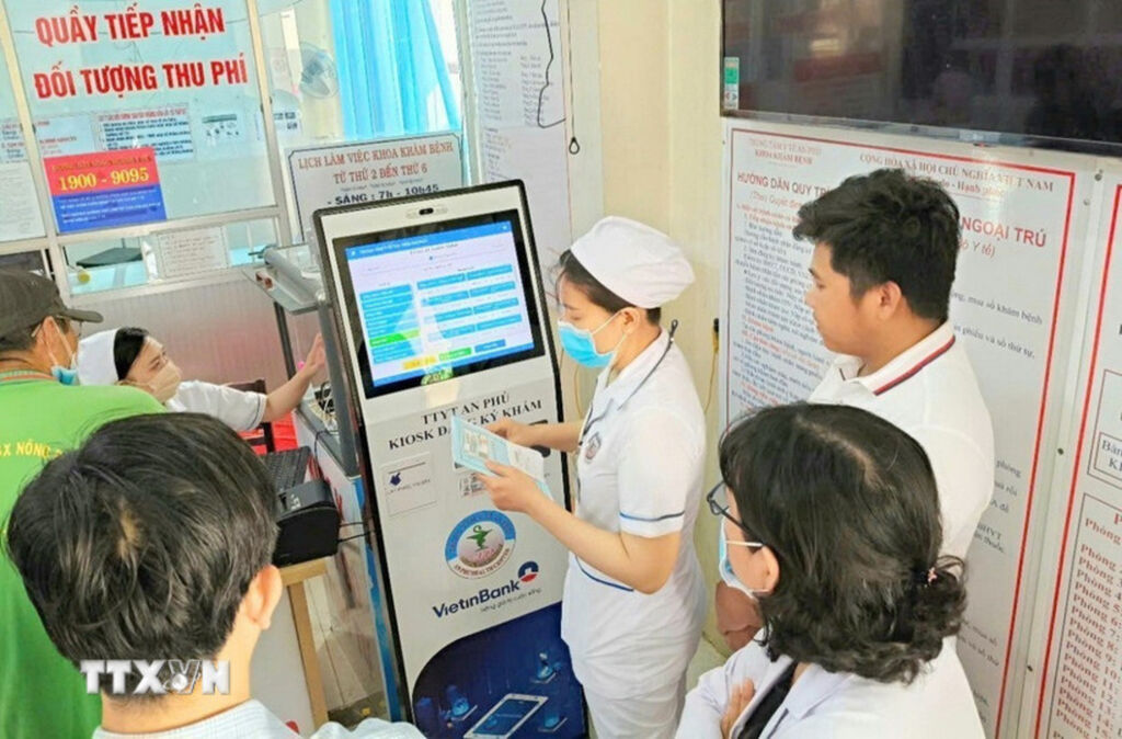 C&aacute;n bộ, nh&acirc;n vi&ecirc;n Trung t&acirc;m y tế An Ph&uacute;, An Giang, hướng dẫn người d&acirc;n đăng k&yacute; kh&aacute;m chữa bệnh bằng kiốt th&ocirc;ng minh. Ảnh: C&ocirc;ng Mạo/TTXVN