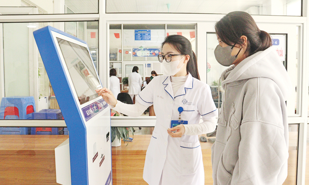 Nh&acirc;n vi&ecirc;n y tế Bệnh viện Ung bướu hướng dẫn người bệnh sử dụng kiosk th&ocirc;ng minh.