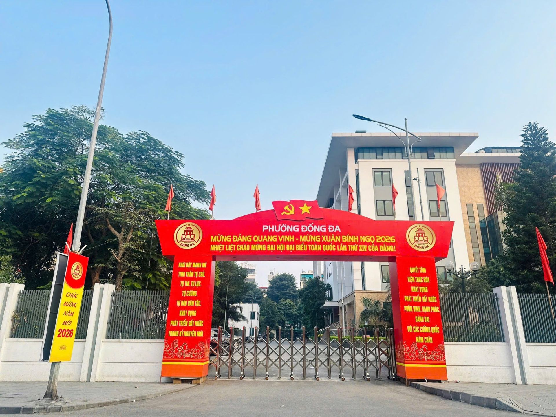 Cổng trụ sở phường Đống Đa rực rỡ sắc đỏ cờ hoa, khẩu hiệu ch&agrave;o mừng Đảng, mừng Xu&acirc;n B&iacute;nh Ngọ 2026 v&agrave; Đại hội XIV của Đảng.