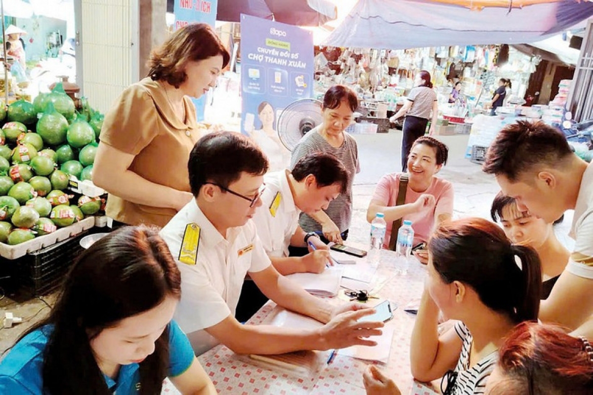 C&ocirc;ng chức Thuế TP. H&agrave; Nội hỗ trợ hộ kinh doanh l&agrave;m thủ tục k&ecirc; khai thuế. Ảnh: KT