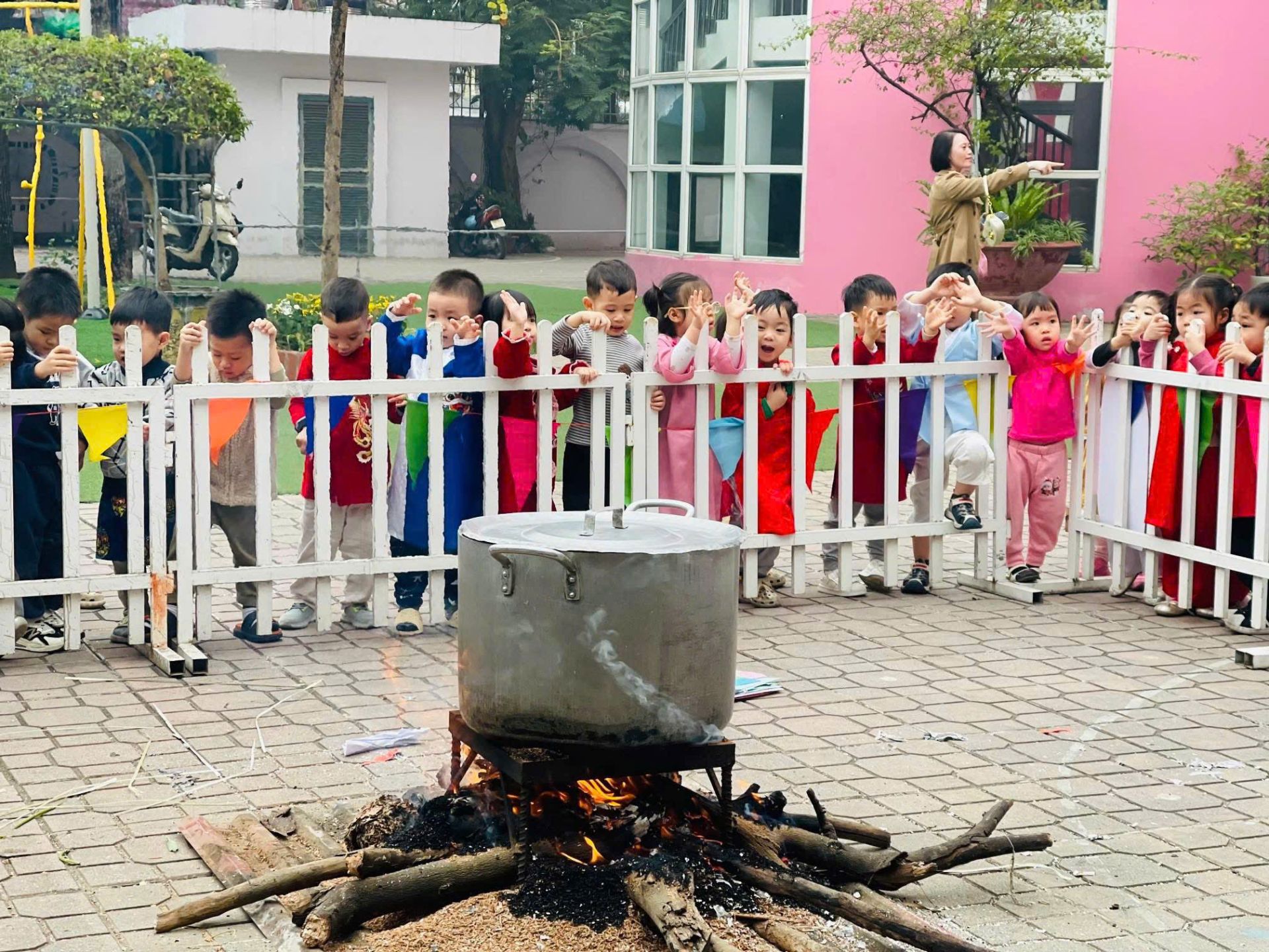 C&aacute;c em nhỏ h&aacute;o hức quan s&aacute;t nồi b&aacute;nh chưng đỏ lửa ngay trong s&acirc;n trường, cảm nhận kh&ocirc;ng kh&iacute; Tết xưa một c&aacute;ch trực quan.