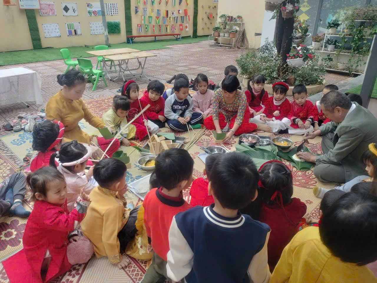 Gi&aacute;o vi&ecirc;n, phụ huynh hướng dẫn trẻ tham gia g&oacute;i b&aacute;nh chưng.