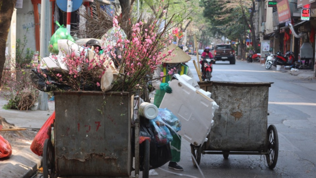 C&agrave;nh đ&agrave;o, c&acirc;y quất v&agrave; r&aacute;c thải sinh hoạt sau Tết được tập kết chờ thu gom tr&ecirc;n một tuyến phố H&agrave; Nội.