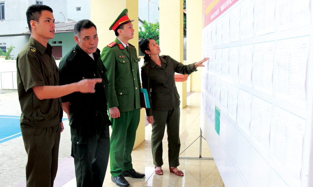 C&aacute;n bộ C&ocirc;ng an x&atilde; Y&ecirc;n Thế c&ugrave;ng th&agrave;nh vi&ecirc;n điểm bầu cử th&ocirc;n B&agrave; Ba nắm lại th&ocirc;ng tin của cử tri từ danh s&aacute;ch được ni&ecirc;m yết.