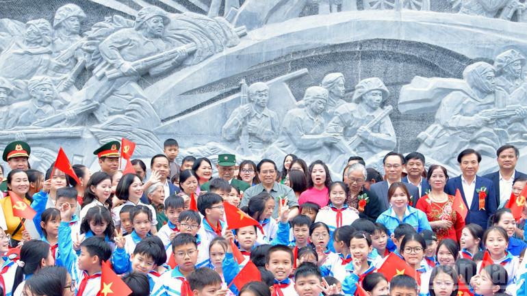 Thủ tướng Phạm Minh Ch&iacute;nh với c&aacute;c ch&aacute;u học sinh tại khu vực bức ph&ugrave; đi&ecirc;u trong Khu di t&iacute;ch Trung t&acirc;m đề kh&aacute;ng Him Lam. (Ảnh: THANH GIANG)