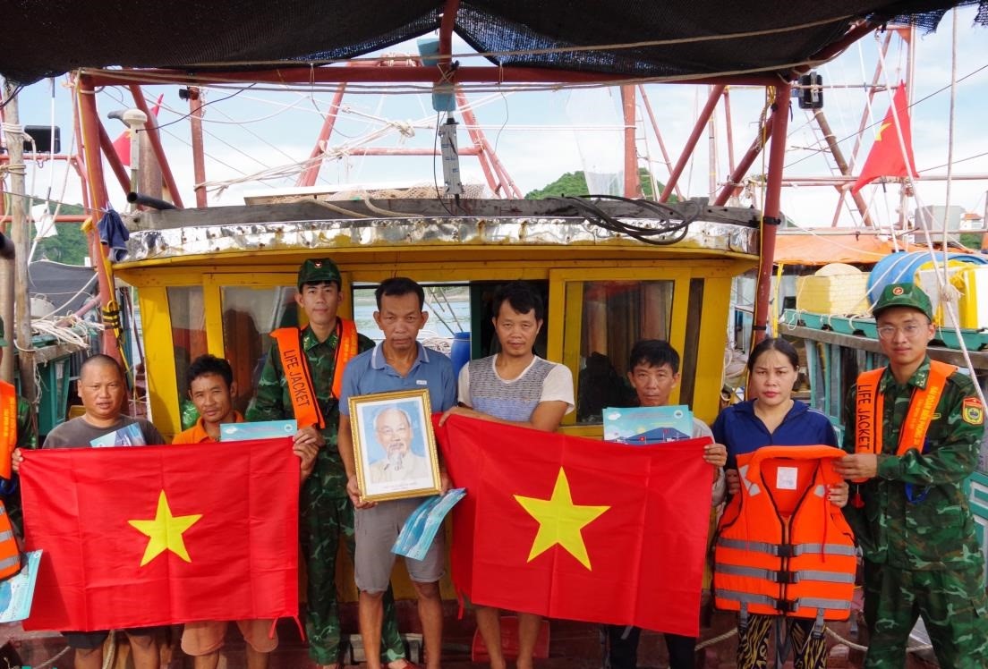C&aacute;n bộ Hải đo&agrave;n Bi&ecirc;n ph&ograve;ng 38 tặng cờ Tổ quốc v&agrave; ảnh B&aacute;c Hồ cho ngư d&acirc;n vươn khơi b&aacute;m biển. Ảnh: Văn Vinh