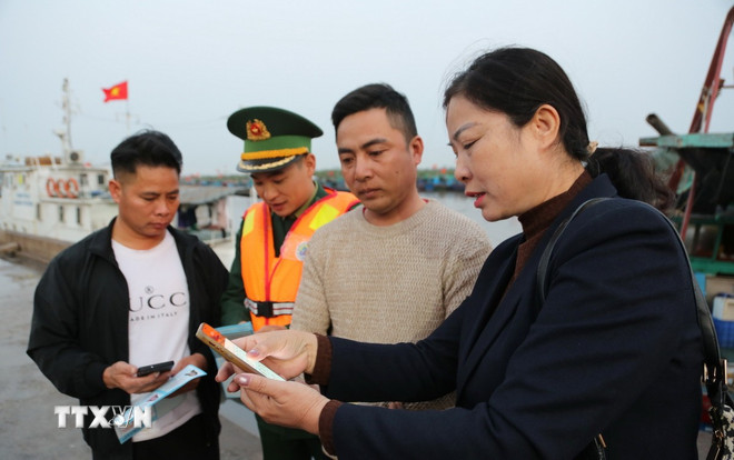 Đại diện Tổ bầu cử số 10, phường Đồ Sơn, th&agrave;nh phố Hải Ph&ograve;ng, hướng dẫn ngư d&acirc;n tiếp cận th&ocirc;ng tin về bầu cử tr&ecirc;n VNeID. (Ảnh: Minh Thu/TTXVN)