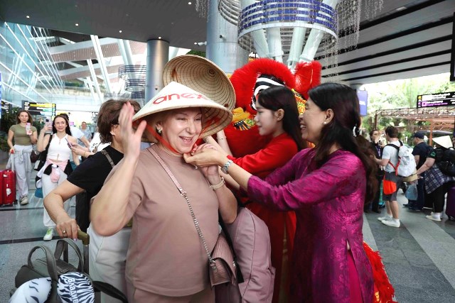 Tặng n&oacute;n l&aacute; v&agrave; hoa cho du kh&aacute;ch.