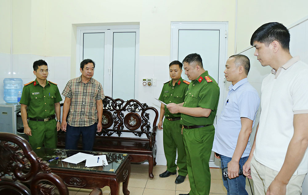 Cơ quan Cảnh s&aacute;t điều tra C&ocirc;ng an tỉnh kh&aacute;m x&eacute;t nơi l&agrave;m việc của Ho&agrave;ng Văn Huấn (&aacute;o kẻ).