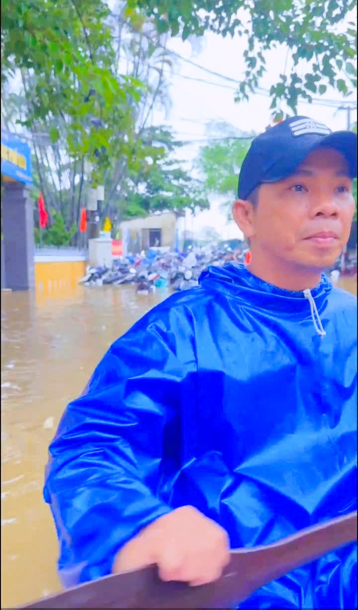 &Ocirc;ng Nguyễn Văn Quốc- Trưởng Ban c&ocirc;ng t&aacute;c Mặt trận tổ 13 ch&egrave;o thuyền đi cứu gi&uacute;p d&acirc;n trong đợt lũ lụt 10/2025 (sau lưng &ocirc;ng h&agrave;ng trăm xe, m&aacute;y để tr&ecirc;n cầu Ph&uacute; Lưu tr&aacute;nh lụt bị ngập lụt to&agrave;n bộ khi nước tr&agrave;n qua cầu)
