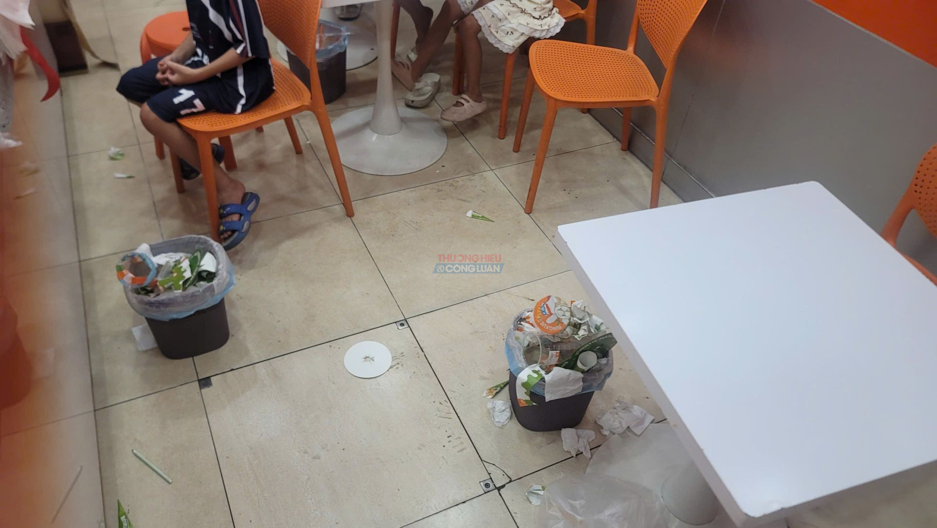 Th&ugrave;ng r&aacute;c đầy tr&agrave;n được đặt ngay dưới gầm b&agrave;n v&agrave; s&aacute;t khu vực kh&aacute;ch sử dụng đồ uống tại BingXue Dương Nội.