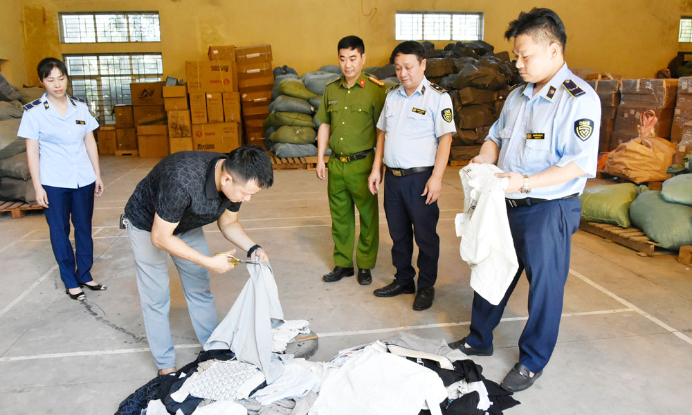Chủ hộ kinh doanh thực hiện ti&ecirc;u hủy h&agrave;ng h&oacute;a vi phạm về nh&atilde;n hiệu trước sự chứng kiến của c&aacute;c lực lượng chức năng.