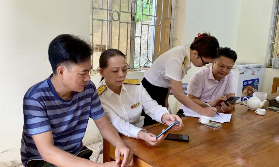 C&ocirc;ng chức ng&agrave;nh Thuế hỗ trợ người nộp thuế c&agrave;i đặt ứng dụng eTax Mobile. Ảnh: KT
