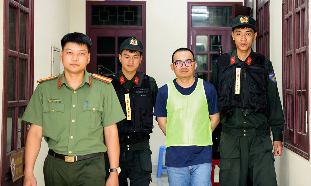 Lực lượng chức năng dẫn giải đối tượng cầm đầu đường d&acirc;y tại Việt Nam - Đinh Đức Phụng (biệt danh Simon) tại cơ quan điều tra. Sau