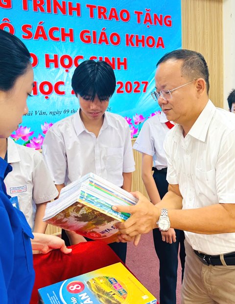Thầy gi&aacute;o Dương Phượng Cầu - Hiệu trưởng trường THCS Đ&agrave;m Quang Trung trao tặng s&aacute;ch gi&aacute;o khoa.