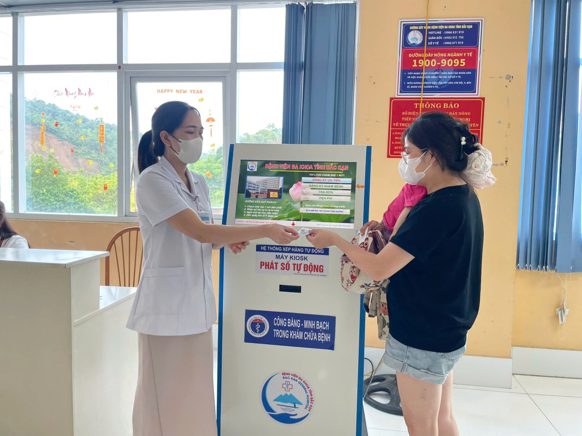 C&aacute;n bộ ng&agrave;nh Y tế hướng dẫn người d&acirc;n lấy số tự động l&agrave;m thủ tục kh&aacute;m chữa bệnh tại Bệnh viện Đa khoa Bắc Kạn. Ảnh: